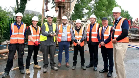 Wye Valley NHS Trust Men proudly standing in front of a boring machine