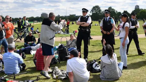 Getty Images Police speak to a large group gathered in a park in central London