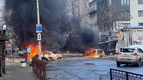 Reuters Cars burn on a street after a Russian military strike, amid Russia's attack of Ukraine, in Kherson, Ukraine (December 24, 2022)