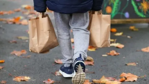 PA Media Child carrying lunch parcels