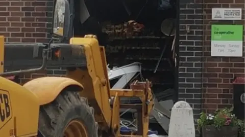 Dave Wright JCB near damaged shop