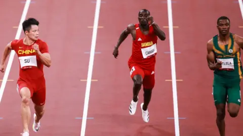 Getty Images Su Bingtian of China, Ebrima Camara of Gambia, Gift Leotlela of South Africa compete in the Men's 100m Round 1 - Heat 4 on day eight of the Tokyo 2020 Olympic Games at Olympic Stadium on July 31, 2021 in Tokyo, Japan.