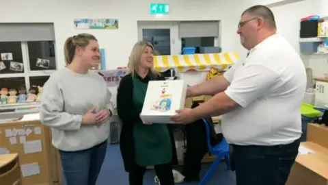 Ian Palmer/BBC Lewis Steeper presents the LifeVac device to staff at a nursery in Ashford