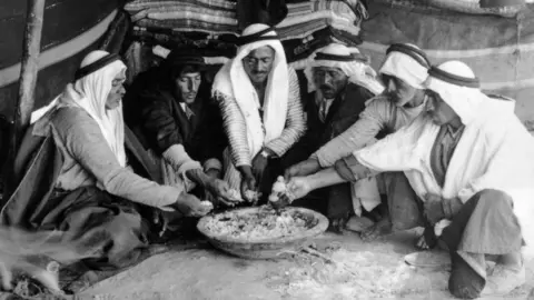 Getty Images A group of six Arab men share a meal in Jericho, Palestine, in about 1925