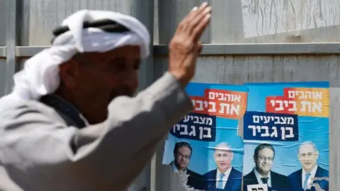 AFP Palestinian gestures next to Israeli election posters in Hebron (07/09/19)