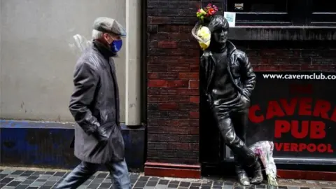 Reuters A man walks past John Lennon statue in Liverpool