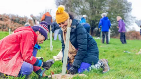 Daisy Brasington A woman and child kneeling on the grass to plant seeds