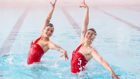 PA Media Rebecca Richardson (left) and Genevieve Florence, members of the Aquabatix synchronised swimming team during a practice session in the swimming pool at Clissold Leisure Centre, north London, which has reopened to the public