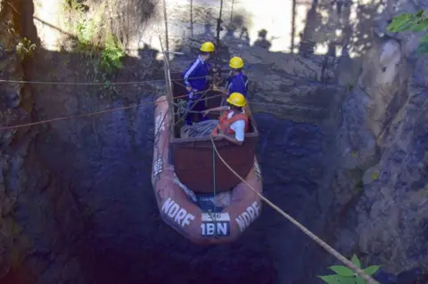 Getty Images Indian navy divers go down into the mine with a pulley during rescue operations.