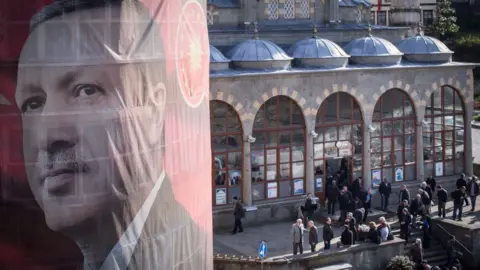 Getty Images Men exit a mosque after afternoon prayer behind a banner showing the portrait of Turkish President Recep Tayyip Erdogan hanging from a building on 10 April 2017 in Rize, Turkey.