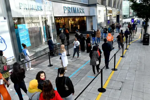 PA Media Customers queue to enter a Primark store