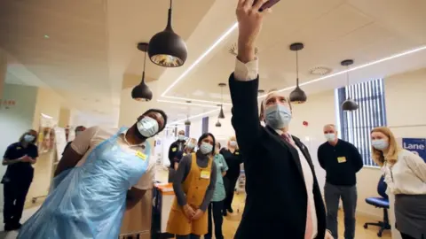 PA Media Health Secretary Matt Hancock takes a selfie with the Vaccine Hub staff during a visit to the Queen Elizabeth Hospital in Birmingham