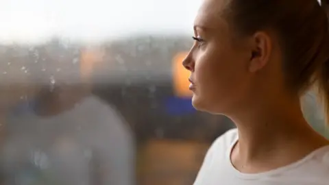 Getty Images Woman looking out of a window