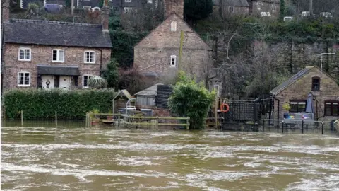 PA Media The Vic Haddock boat house (right) is flooded along the swollen River Severn