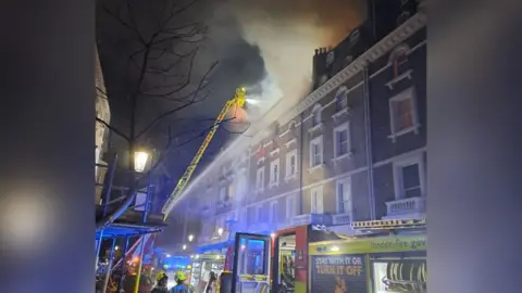 London Fire Brigade Firefighters battle blaze which is sweeping through building in South Kensington