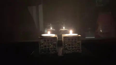 Ari Gottesmann A pair of candles shine brightly in a dark room to commemorate Kristallnacht