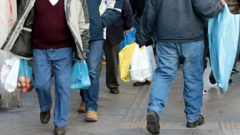 EPA Consumers carry plastic bags on a street of central Athens