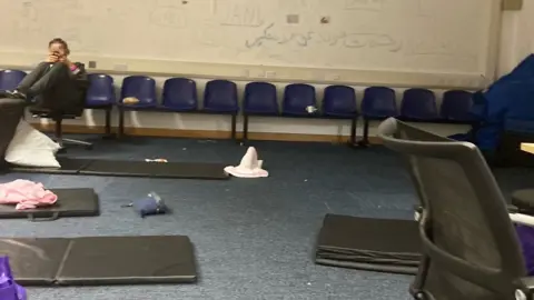 A person sits on a plastic chair inside the unnamed Home Office facility in Kent.