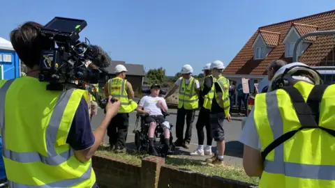 Wayne Bavin/BBC Luke Goold-Hannatt with construction workers around him