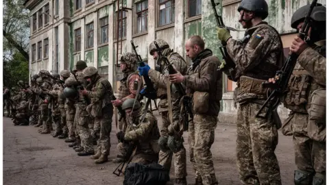 YASUYOSHI CHIBA Ukrainian soldiers unload their guns as they arrive at an abandoned building to rest and receive medical treatment after fighting on the front line for two months near Kramatorsk, eastern Ukraine on April 30, 2022.