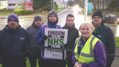 Healthcare workers hold placards outside Altnagelvin Hospital in Londonderry