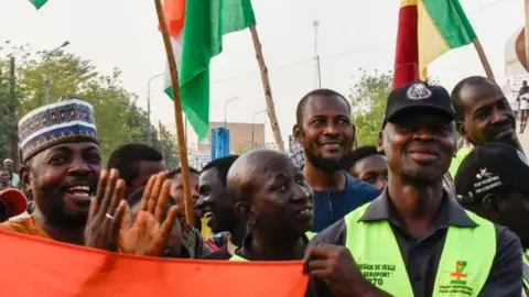 AFP Supporters of the Alliance Of Sahel States (AES) hold up flags as they celebrate Mali, Burkina Faso and Niger leaving the Economic Community of West African States (ECOWAS) in Niamey on January 28, 2024