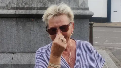 Seth Spain/BBC Sally Butcher, pinching her nose to guard against the smell