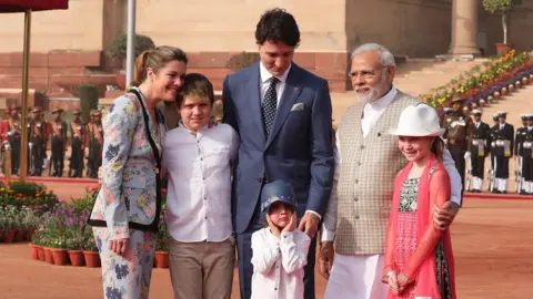 EPA Hadrien Trudeau pulling his hat over his face in a photo with Narendra Modi
