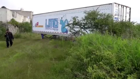 Reuters A police officer walks alongside an abandoned trailer full of bodies in Tlajomulco de Zuniga, Jalisco, 15 September 2018