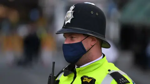 AFP A police officer wearing a protective face covering patrols in Soho in London