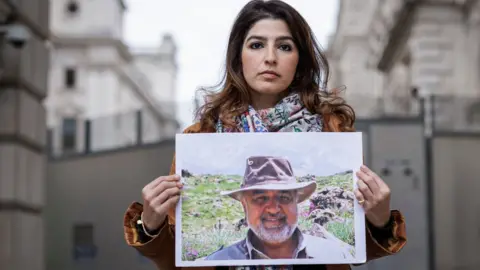 Getty Images Roxanne Tahbaz holds a photograph of her father, Morad Tahbaz, outside the Foreign, Commonwealth and Development Office