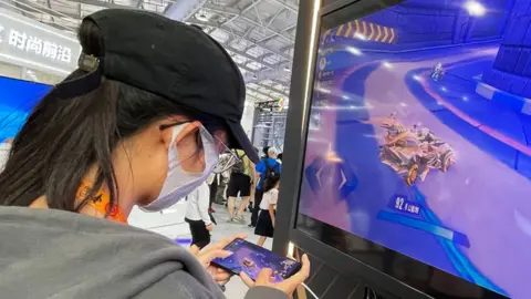 Getty Images A visitor plays a mobile game at the booth of Tencent in Beijing, China.