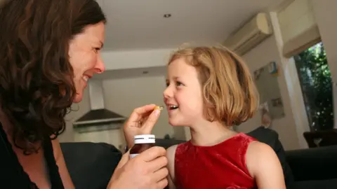 Getty Images mum giving daughter a vitamin tablet