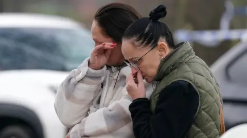 PA Media Upset mourners look at the flowers and tributes near to Babbs Mill Park in Kingshurst