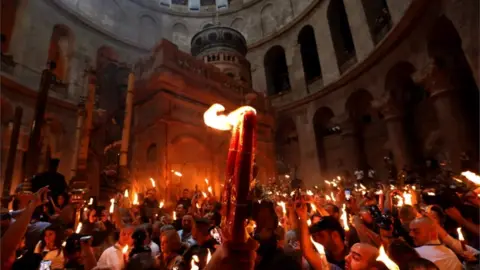 AFP/Getty Orthodox Christians holding candles aloft in the Church of the Holy Sepulchre in Jerusalem