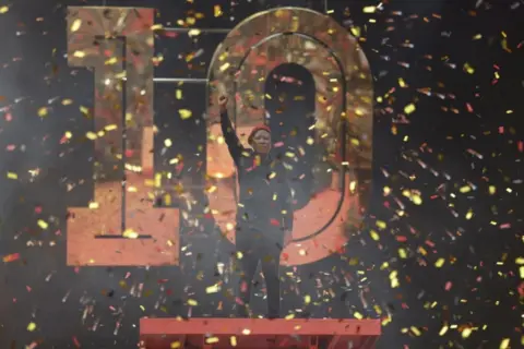 Guillem Sartorio/AFP Man standing on stage with fist raised up, 29 July 2023