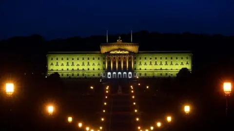 Press Eye Stormont bathed in yellow light