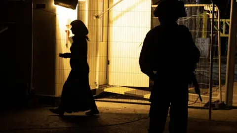 IDF A woman walks past an Israeli soldier