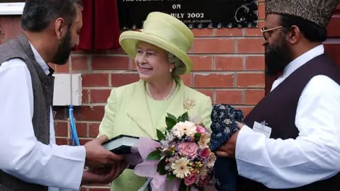 Getty Images The Queen accepting a Quran during her visit to a mosque in 2002