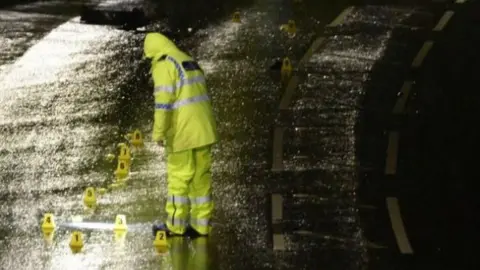 Matt Gilley Forensic examiners on a dark, wet road