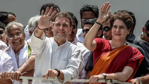 Getty Images Rahul Gandhi and Priyanka Gandhi wave at the crowd in the road show after Rahul Gandhi filing nominations from Wayanad district on April 4, 2019