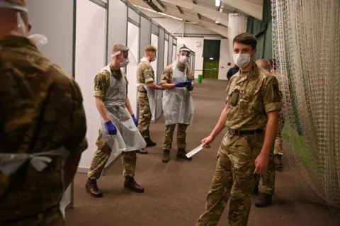 Oli Scarff / AFP Soliders wear PPE in a testing centre