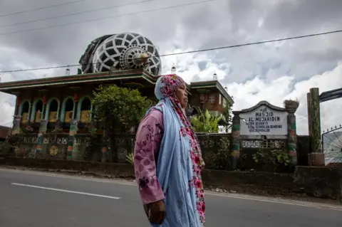 Ulet Ifansasti/ Getty Images A woman walks through a collapsed mosque in Sembalun in Lombok island, Indonesia