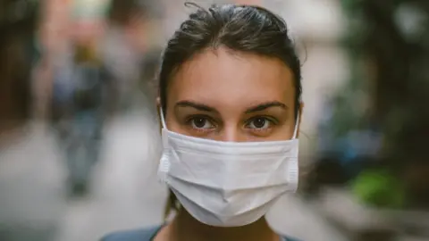 Getty Images Woman wearing a surgical mask