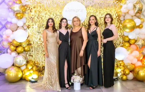 Abramov Sergey (From left to right) Sofiia, Aliesia, their former teacher Svetlana, Iryna and Yuliia in Mykolaiv, celebrating their prom in July 2023
