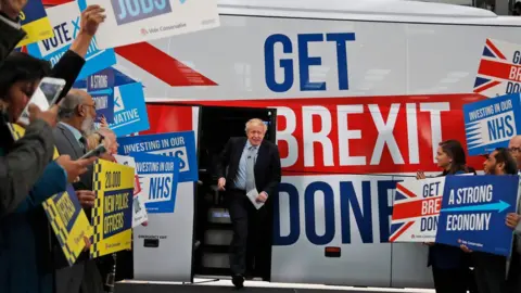 AFP Boris Johnson comes out of a bus which bears the slogan "get Brexit done" in Union Jack colours