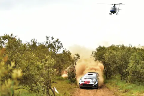AFP A helicopter about a car being driving by Sebastien Ogier and co-driver Julien Ingrassia during the Safari Rally near Lake Naivasha, Kenya - Friday 25 June 2021