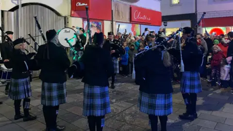 Pipe ban playing in front of a a crowd