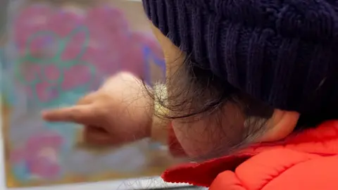 Getty Images Child with learning disabilities points at picture