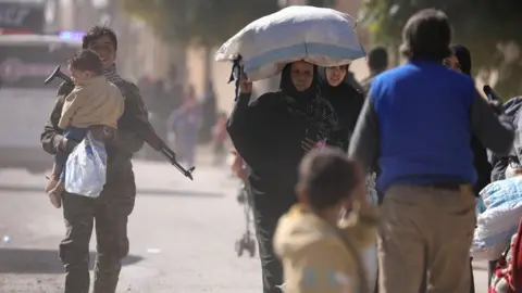 Reuters A woman holds her belongings as she flees Raqqa, Syria (16 October 2017)